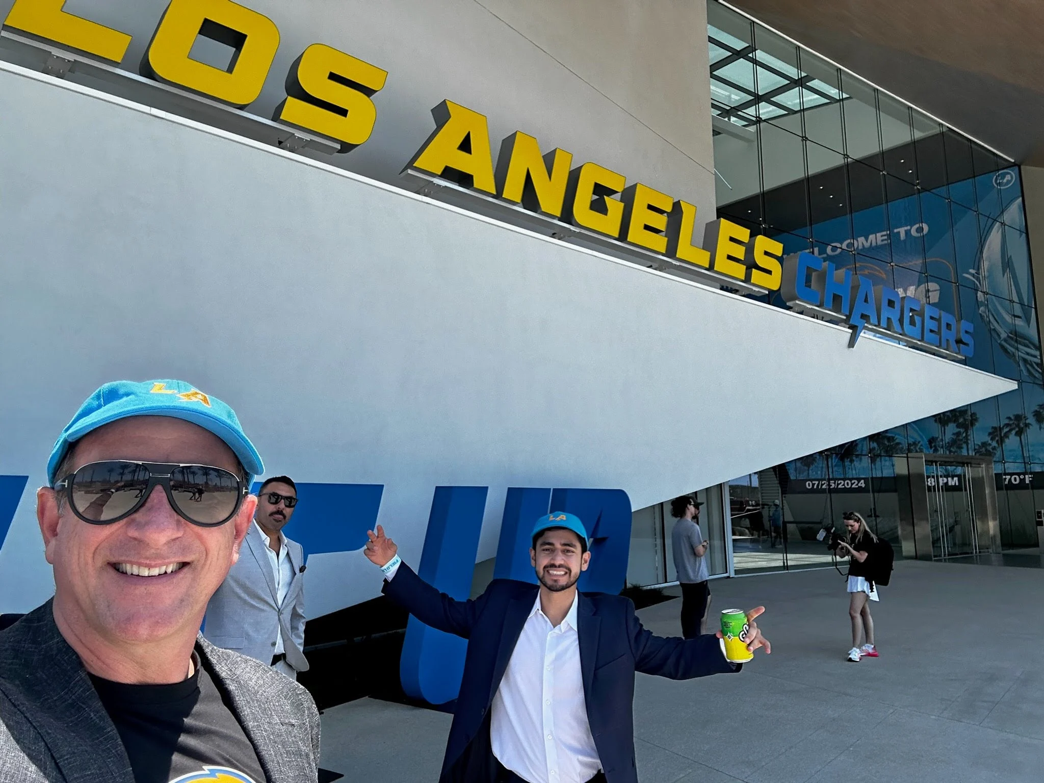 Ed Kaminsky and two others beneath the Los Angeles Chargers sign outside the team facility in El Segundo